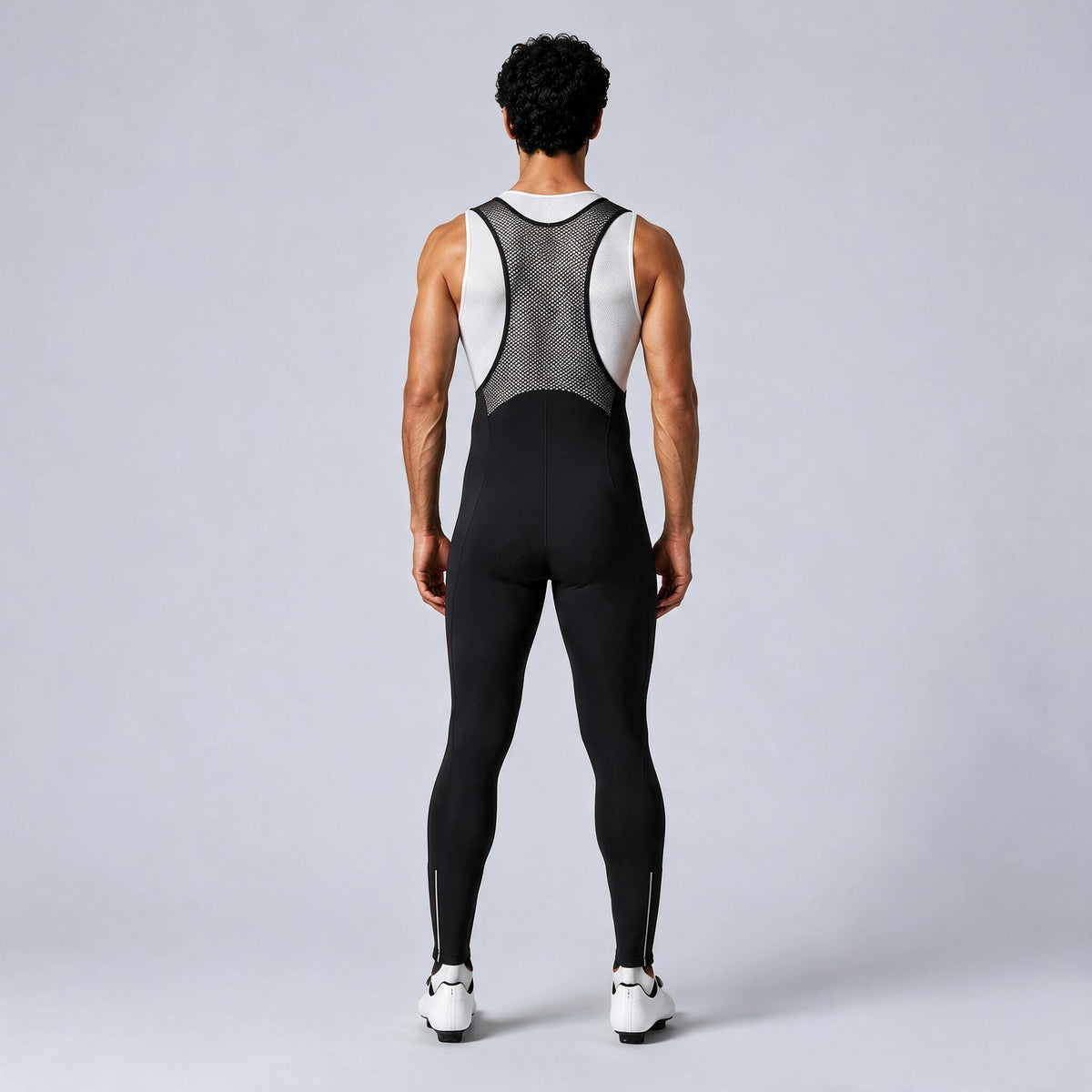 Back view of a model wearing black men's winter fleece road cycling bib tights.