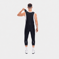 Rear view of a model lifting the shoulder strap of black men's classic 3/4 cycling bib shorts.