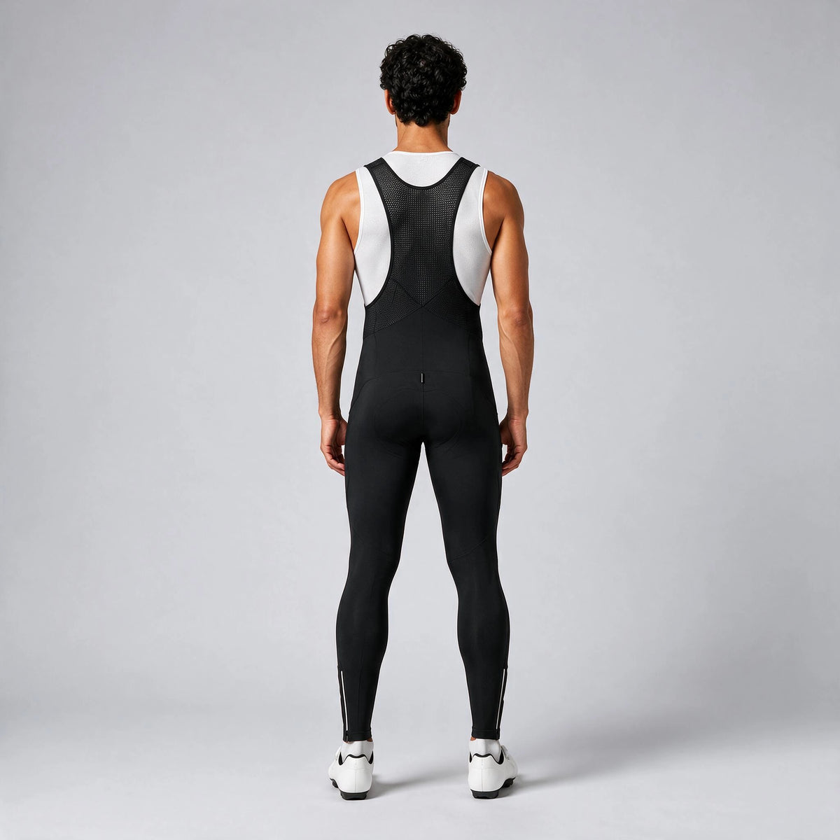 Back view of a model wearing black men's winter thermal road cycling bib tights.