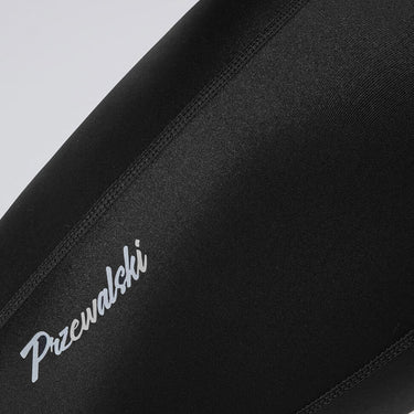 Close-up of Przewalski Men's Classic Cycling 3/4 Bib Shorts leg panel with logo, black fabric and flatlock seams.